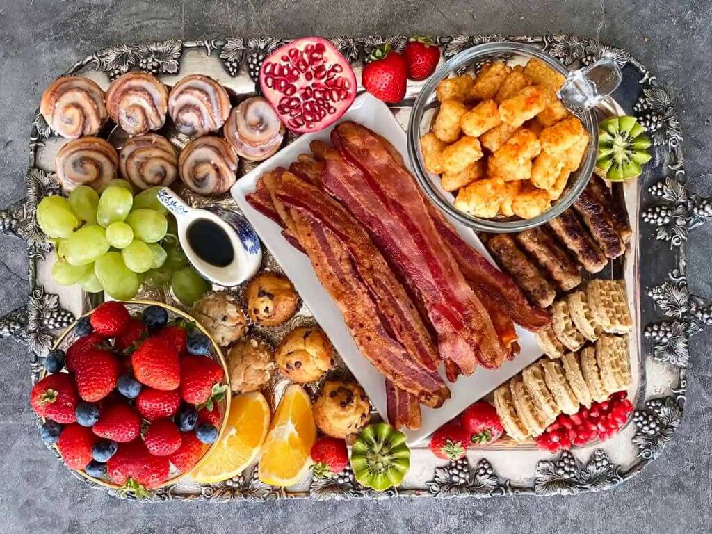 Festive breakfast grazing board with crispy bacon, fruit and pastries