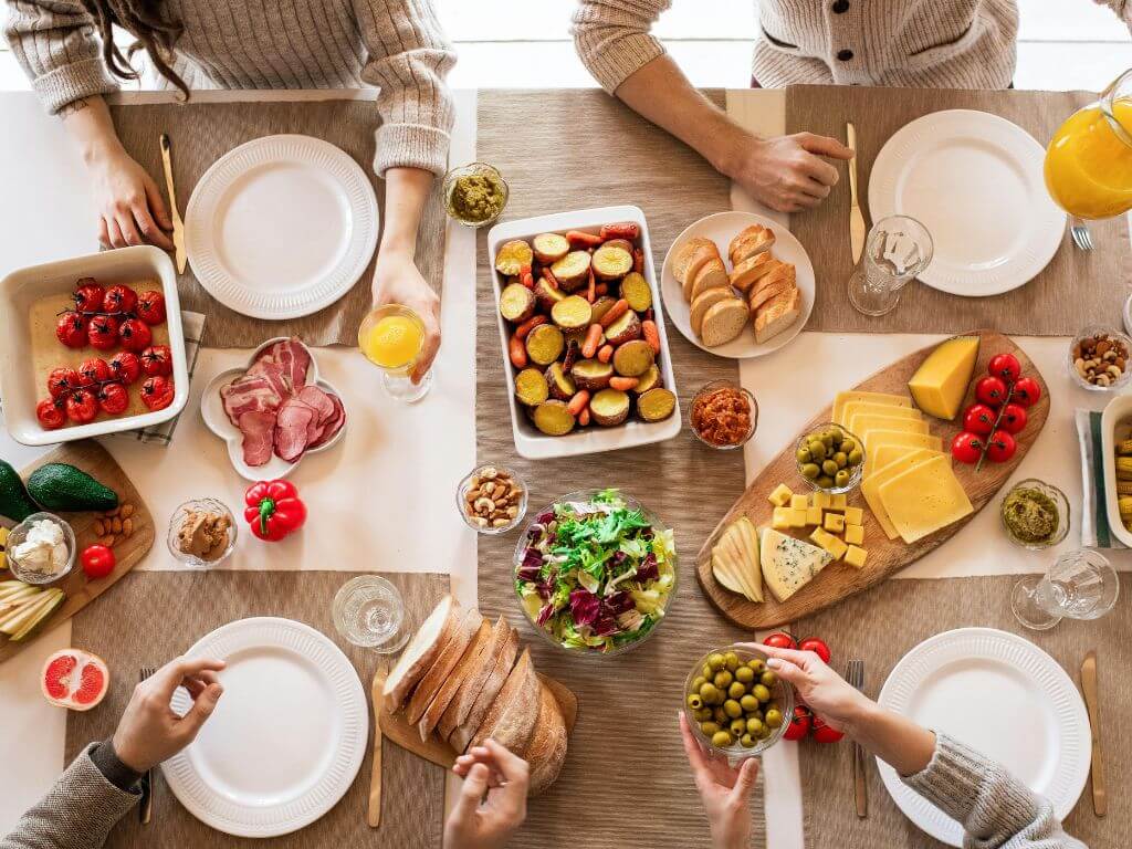 Family-style table spread with bread, salad, cheese and sides representing shared meals at home.